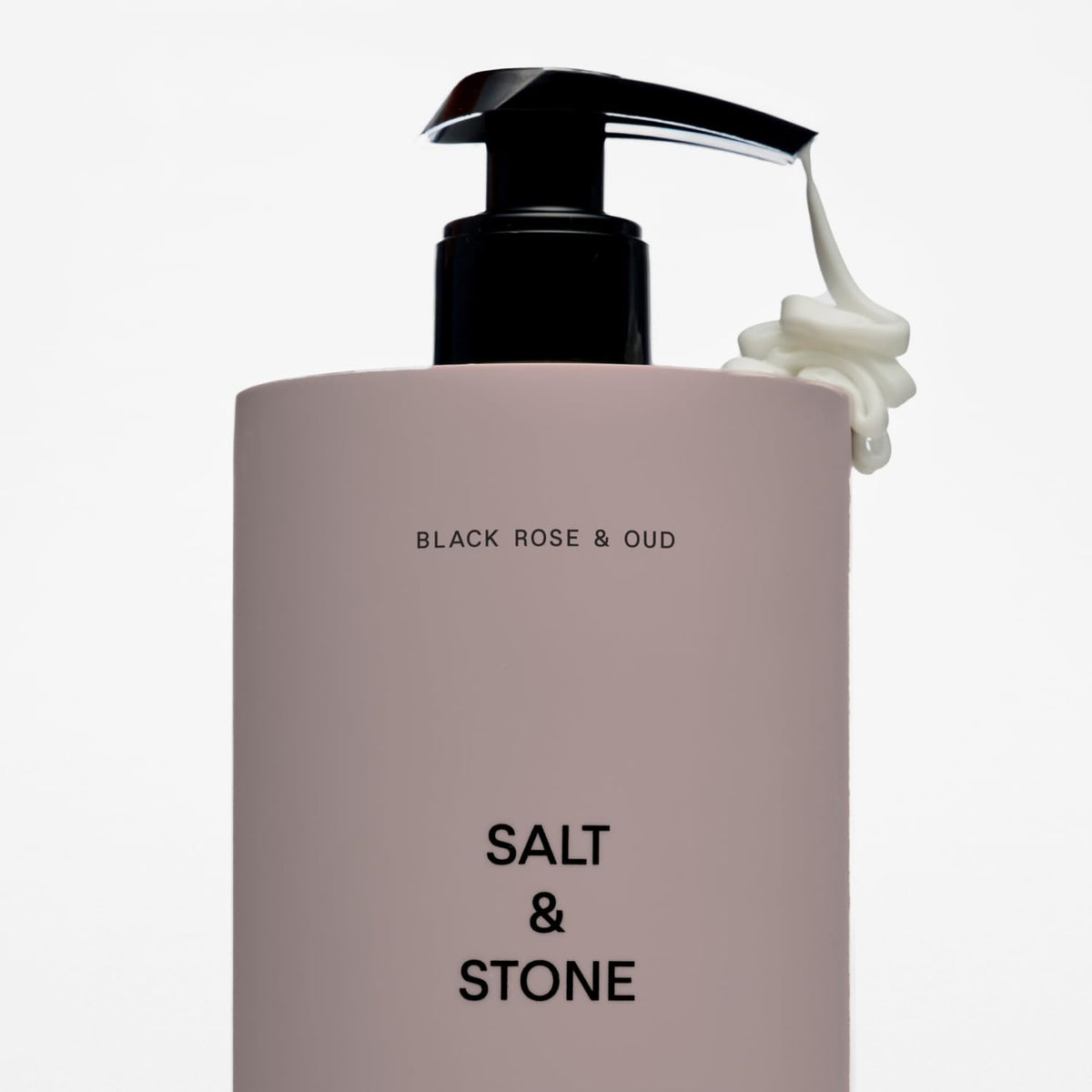 Salt & Stone bottle in hand showing 15.2 fl oz scale and travel-friendly size benefit