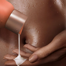 SheaMoisture bottle in shower setting with towel, suggests daily moisturized routine