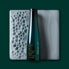 shu uemura art of hair bottle held in hand to illustrate size and easy dispensing