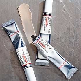 Smashbox lifestyle shot of model applying primer showing lasting makeup benefit