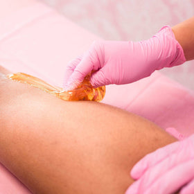 Applying Sugaring NYC paste with spatula for controlled, even application