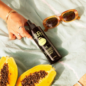 Sun Bum spray application on arm in sunlight, brand keeps skin moisturized