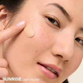 Applying Supergoop! with fingers to show easy spread and mattifying benefit