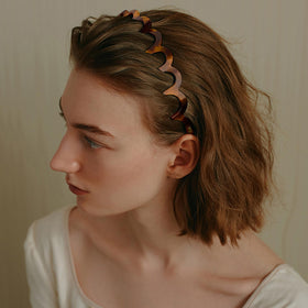 Supgoodom headband beside hand for scale showing compact, portable size benefit