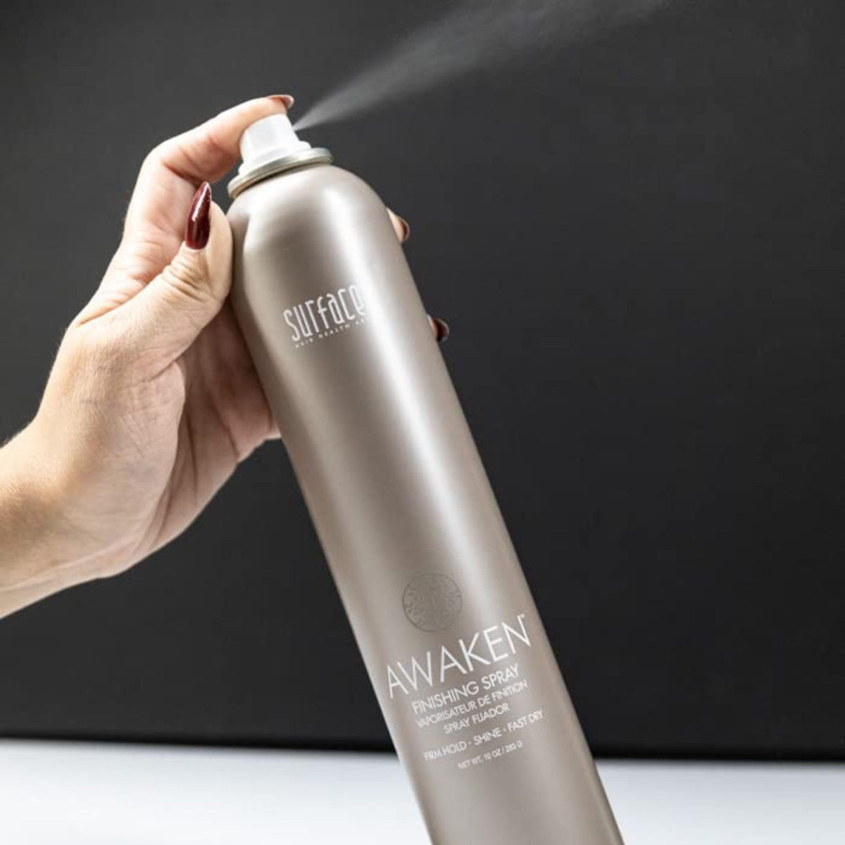 SURFACE bottle held in hand to show 10 oz scale for sizing clarity