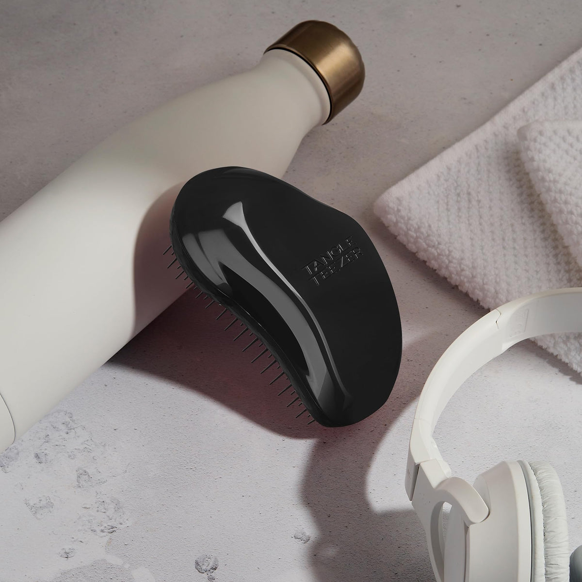 TANGLE TEEZER held in a hand to show size, travel-friendly convenience benefit
