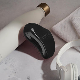 TANGLE TEEZER held in a hand to show size, travel-friendly convenience benefit