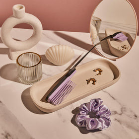 TANGLE TEEZER held in hand to show compact size and travel-friendly convenience