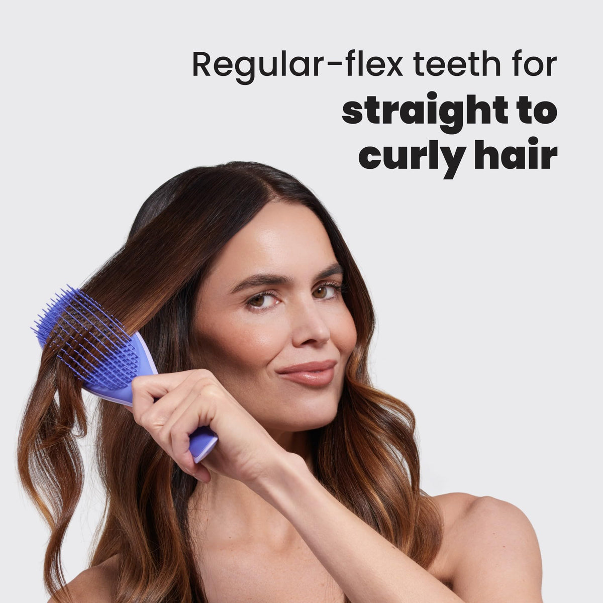 TANGLE TEEZER held in hand for scale showing compact travel-friendly size and comfortable hold