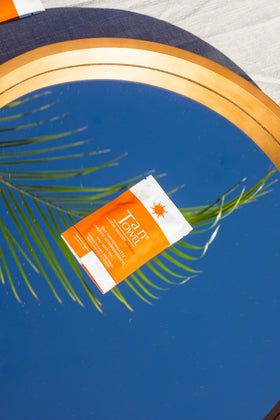 Hand holding a TanTowel towelette for scale and portability, showcasing travel-friendly single-use convenience