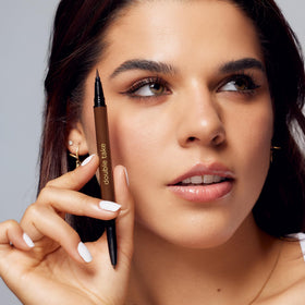 tarte liquid tip applying across eyelid, shows a crisp line for bold definition