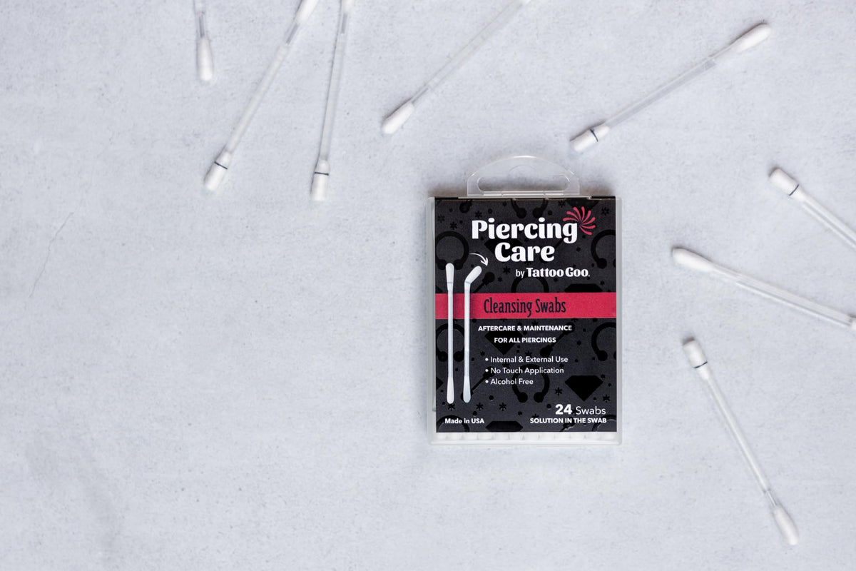 Tattoo Goo swab being applied to an oral piercing for gentle antiseptic cleansing