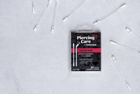 Tattoo Goo swab being applied to an oral piercing for gentle antiseptic cleansing