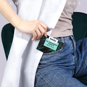 Woman touch-up at mirror using Teenitor blotting sheet for fresh, shine-free skin