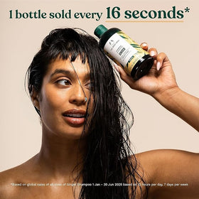 The Body Shop ginger shampoo held in hand to show 13.5 oz scale