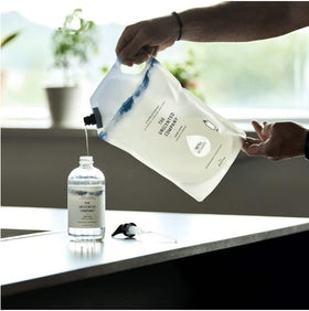 Pouring The Unscented Company refill into a soap dispenser, demonstrating easy low-waste refill