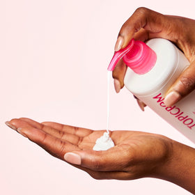 Topicrem bottle next to hand to show 500 ml size and economical benefit