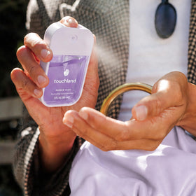 Touchland hand spray used outdoors showing clean hands and refreshing scent
