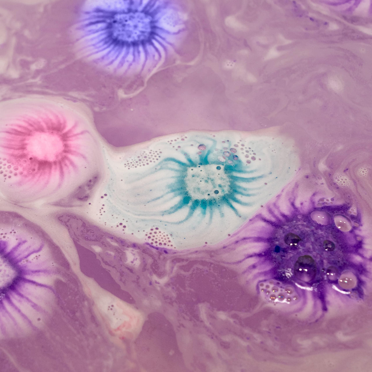 Tub Works mini bath bombs fizzing in tub producing colorful foam and bubbles