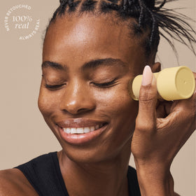 Person applying TULA stick on face outdoors, showing quick reapplication and sun protection benefit