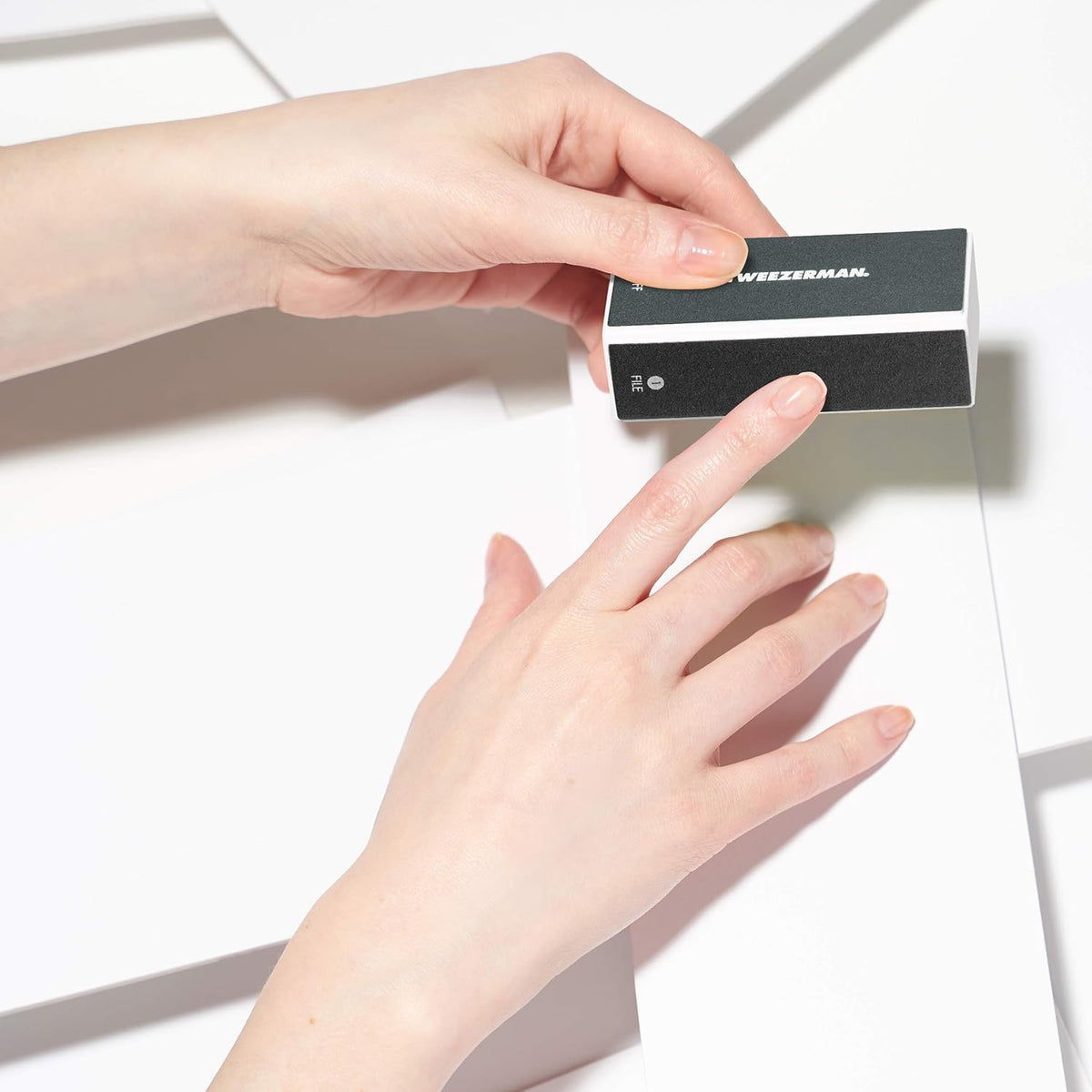 Tweezerman buffer held in hand to show compact size and easy portability benefit
