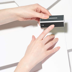 Tweezerman buffer held in hand to show compact size and easy portability benefit