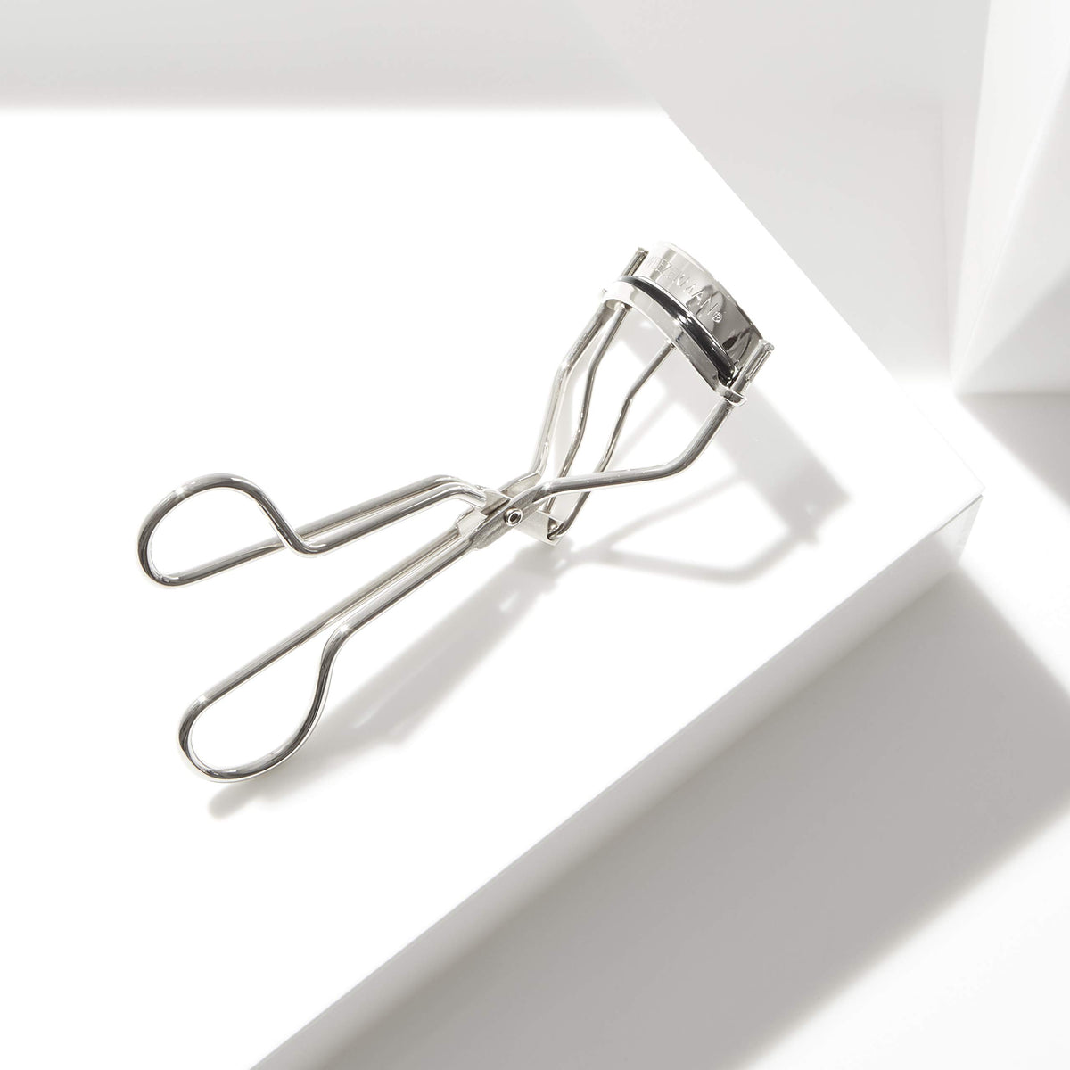 Tweezerman curler held in hand to show compact size and travel convenience