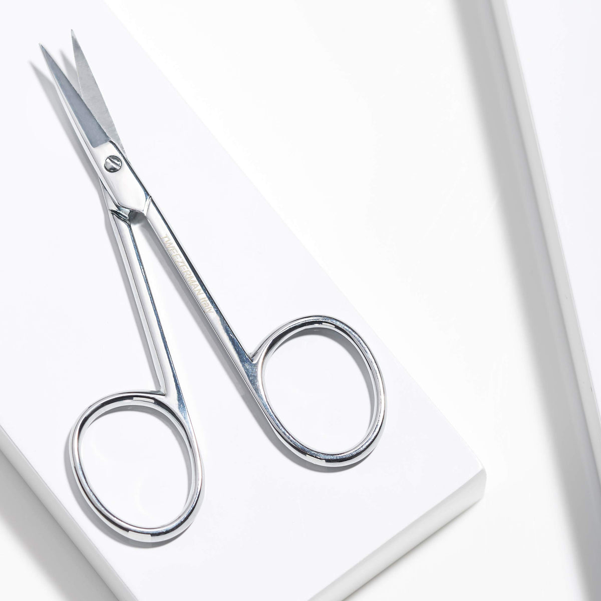 Tweezerman scissors held in hand illustrating size and control for comfortable use