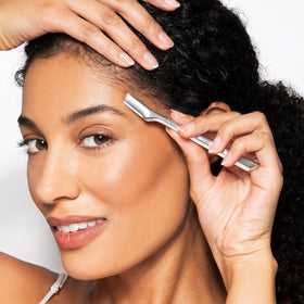 Tweezerman razor held in hand to show compact size and control for accurate eyebrow shaping