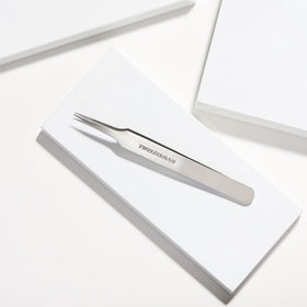 Tweezerman tweezer held in hand illustrating compact size and portability