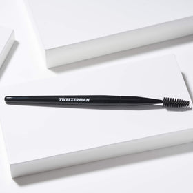Tweezerman spoolie held in hand for scale and easy travel convenience