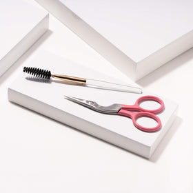 Tweezerman scissors in use trimming brow hair for controlled, natural shaping