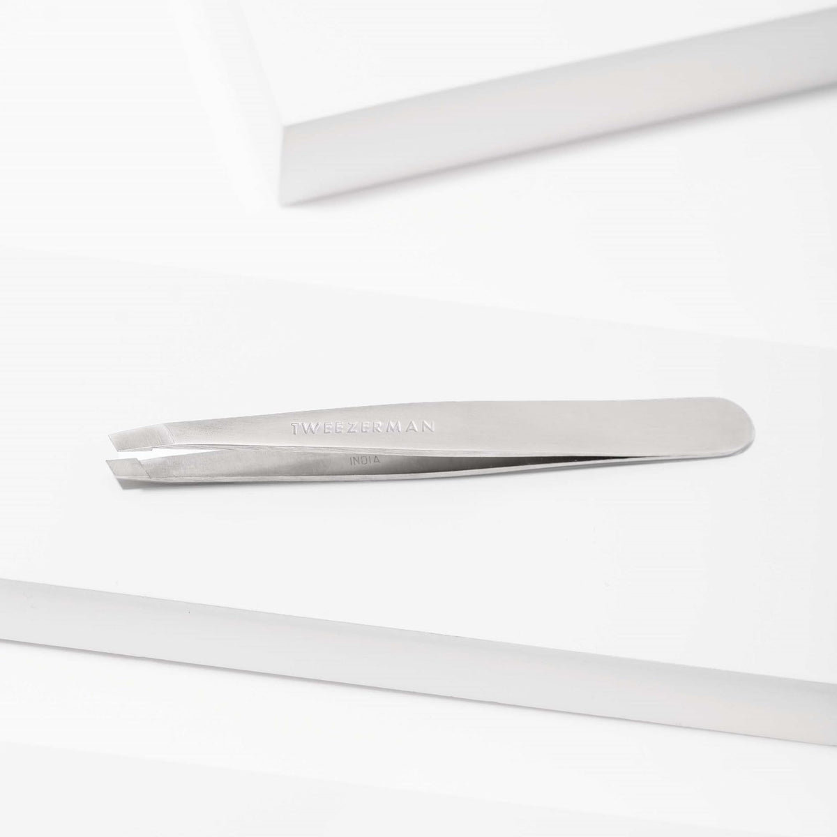 Tweezerman tweezer beside ruler for size comparison and portability benefit
