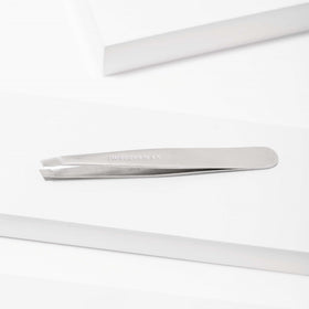 Tweezerman tweezer beside ruler for size comparison and portability benefit