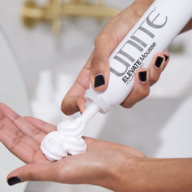 UNITE ELEVATE mousse size comparison in hand showing 6 oz scale for travel-friendly styling benefit