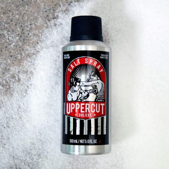 UPPERCUT DELUXE bottle held in hand to show compact 5 fl oz travel-friendly size