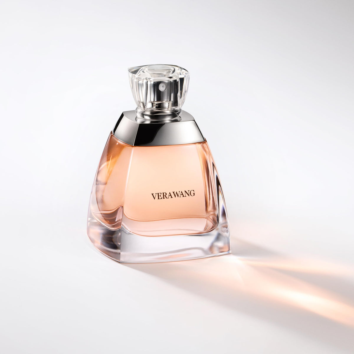 Vera Wang 3.4 fl oz bottle next to common items to show compact travel-friendly size