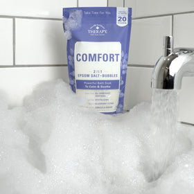 Village Naturals Therapy in bathroom soak scene conveying relaxing home spa benefit