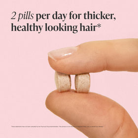 Viviscal tablets in hand for scale showing tablet size and ease of swallowing