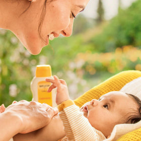 Applying Weleda lotion to baby's arm, calming and softening skin
