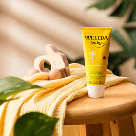 Weleda cream texture on fingertip, demonstrating smooth moisturizing benefit